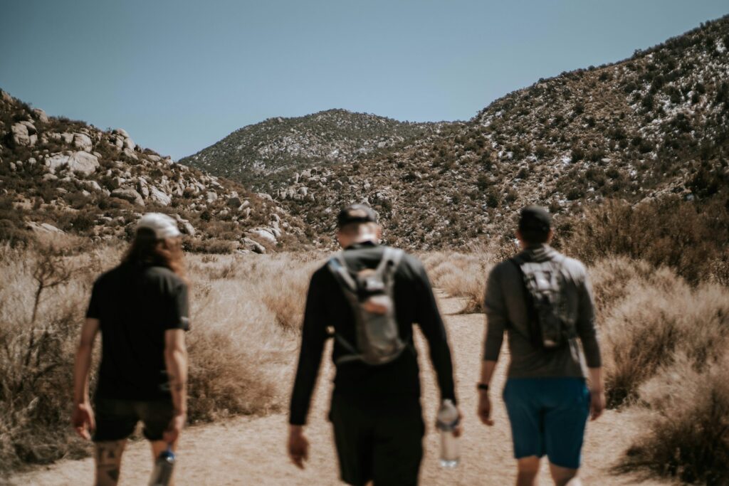 3 men walking on dirt road during daytime